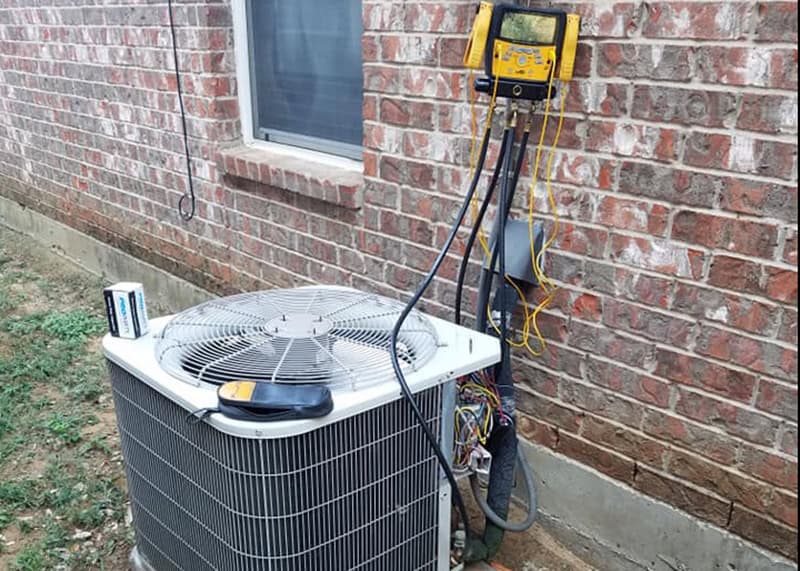 An HVAC technician uses a digital manifold gauge set to diagnose an air conditioner that keeps shutting off at a home in Forney, TX.