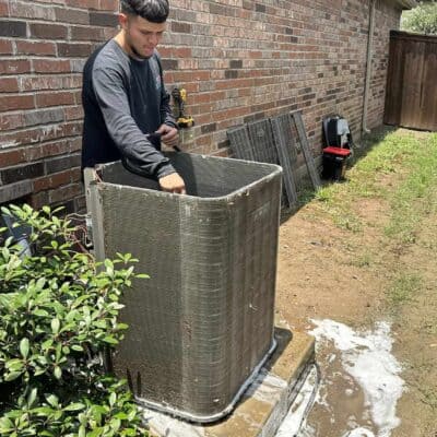 AC technician cleaning an outdoor ac unit during an annual maintenance service