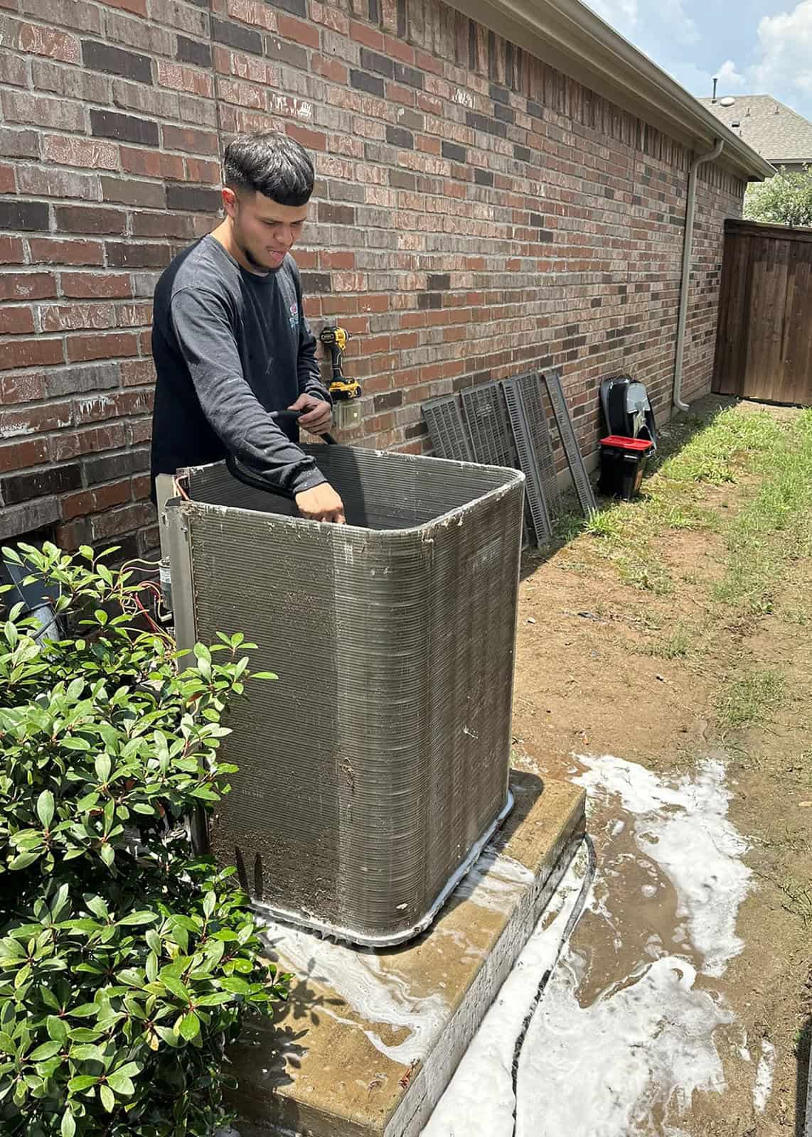 HVAC technician performing AC maintenance with chemical coil cleaning on outdoor unit in Forney, TX – Bolton Heating & Air