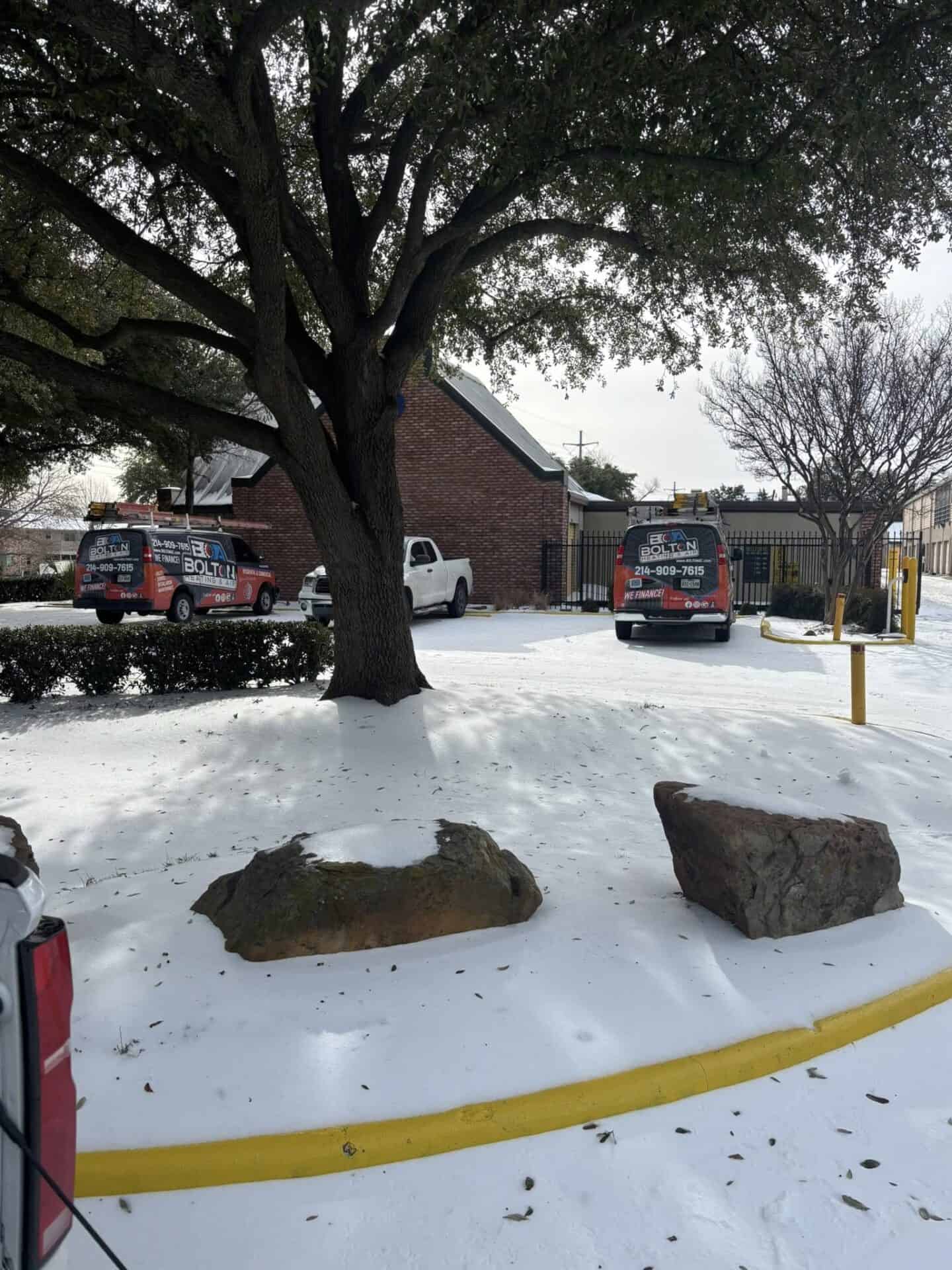 Bolton Heating & Air service vans parked at a snowy HVAC jobsite in Forney, TX during a winter freeze