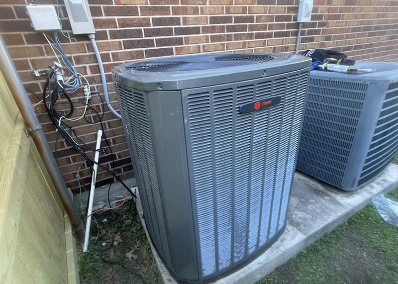 Newly installed Trane outdoor AC condenser on a concrete pad with exposed wiring—showing the installation details professionals must get right.