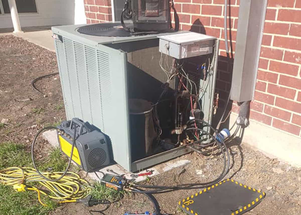 Bolton Heating & Air technician performing HVAC repair on a residential AC condenser unit outside a home in Forney, TX.